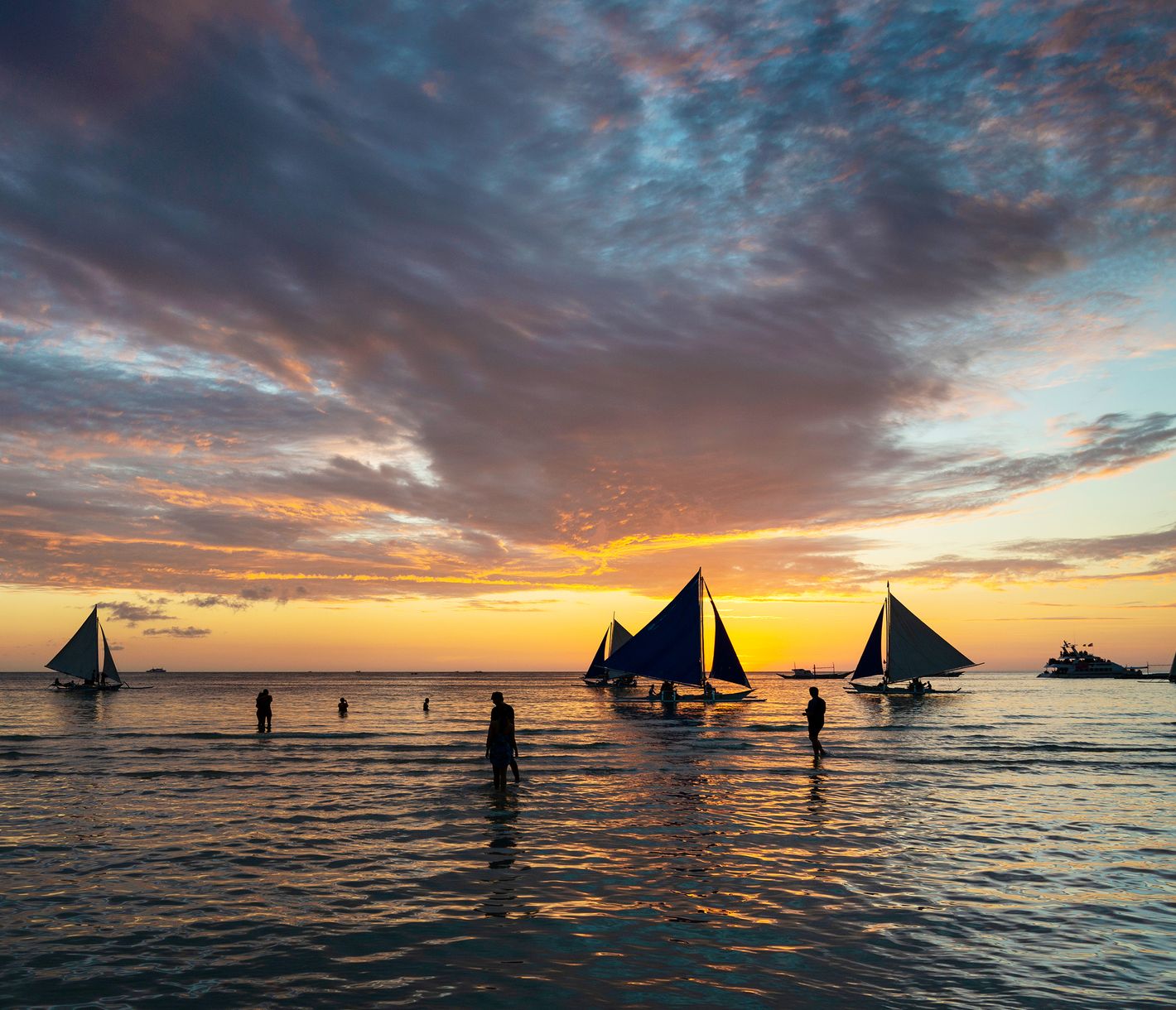 Rund ein halbes Dutzend «Paraw» tummeln sich bei Sonnenuntergang vor den Stränden Boracays.
