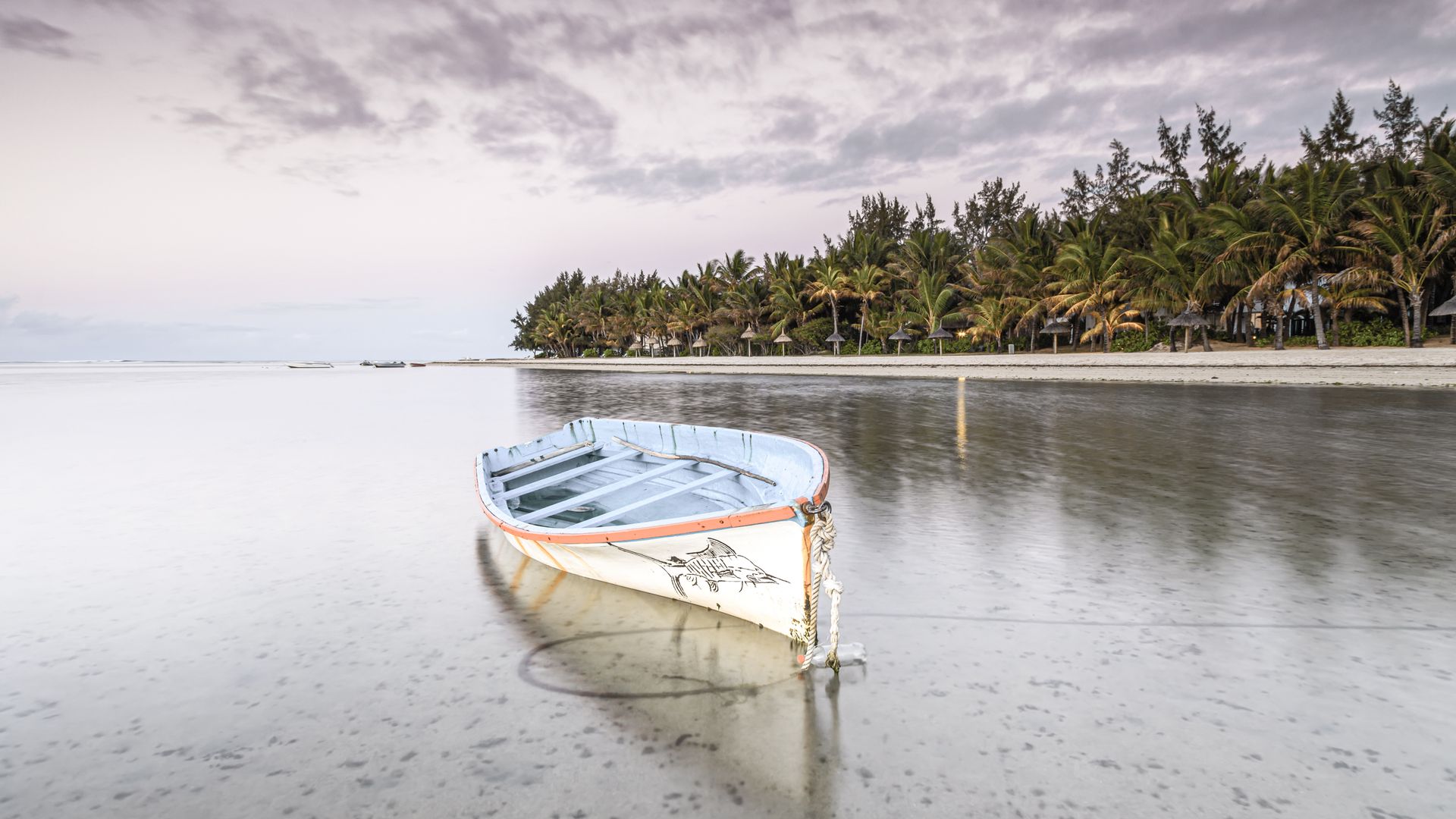 Bateau de pêche baigné par la douce lumière du soleil couchant et bordant la longue plage de Blue Bay.