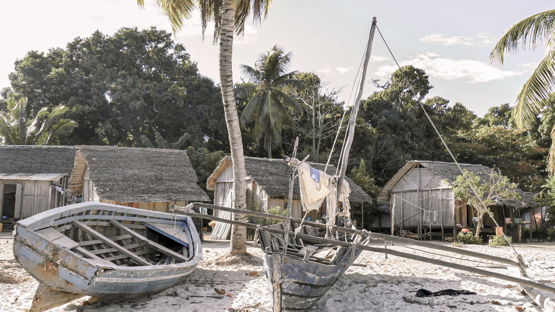 Ein traditionelles Fischerboot vor einfachen Hütten auf Nosy Be