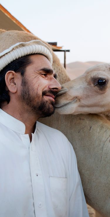 Naher und Mittlerer Osten Reisen - Kamelhirte mit jungem Kamel in der Liwa-Oase