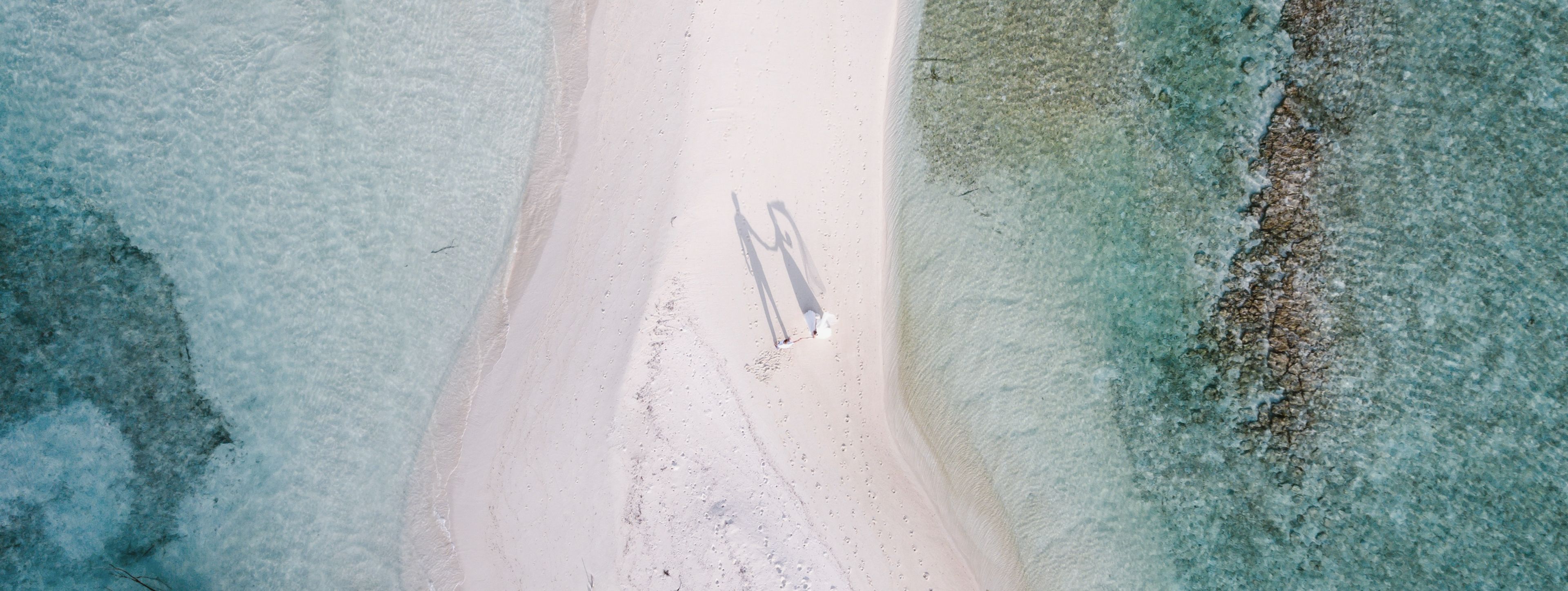 Hand in Hand über Sand, wo die Welt nur Himmel und Meer kennt.