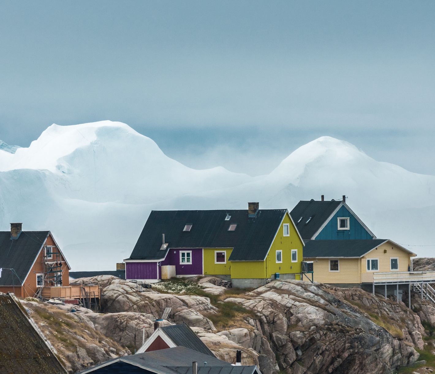 Farbige Häuser thronen vor der Kulisse von gestrandeten Eisbergen in Ilulissat.