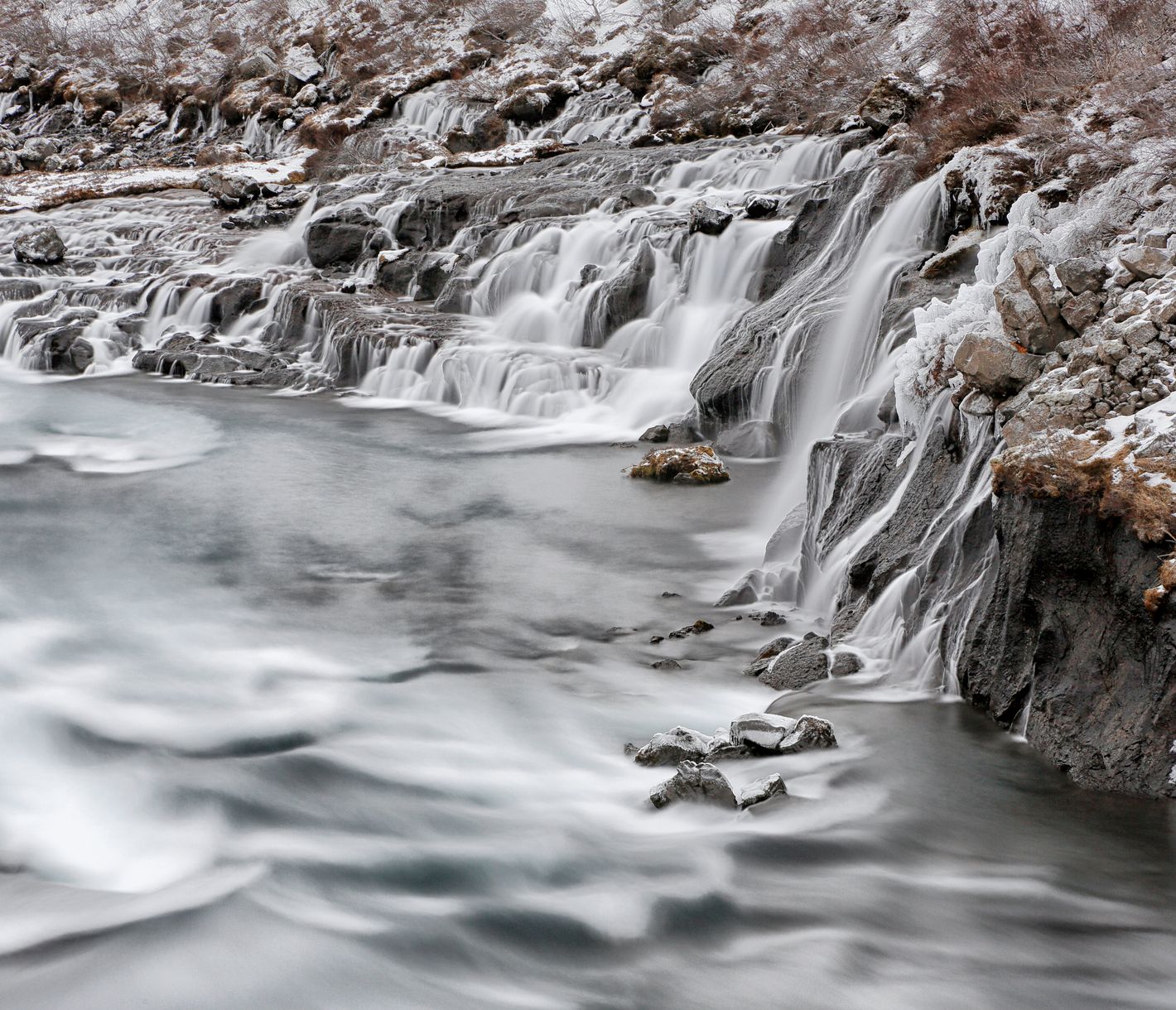Direkt aus einem Lavafeld stürzen unzählige kleine Wasserfälle in den Fluss Hvita.