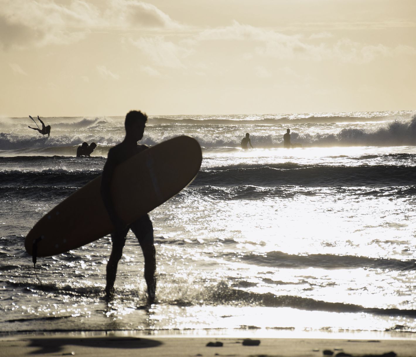 Surfer im Licht der untergehenden Sonne am Strand von St. Leu