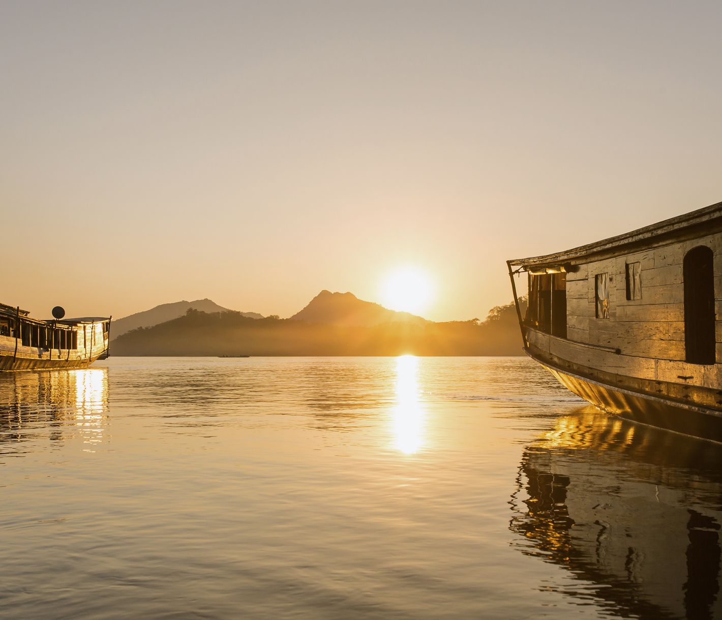 Traditionelle laotische Holzboote an einer Anlegestelle in Luang Prabang bei Sonnenuntergang