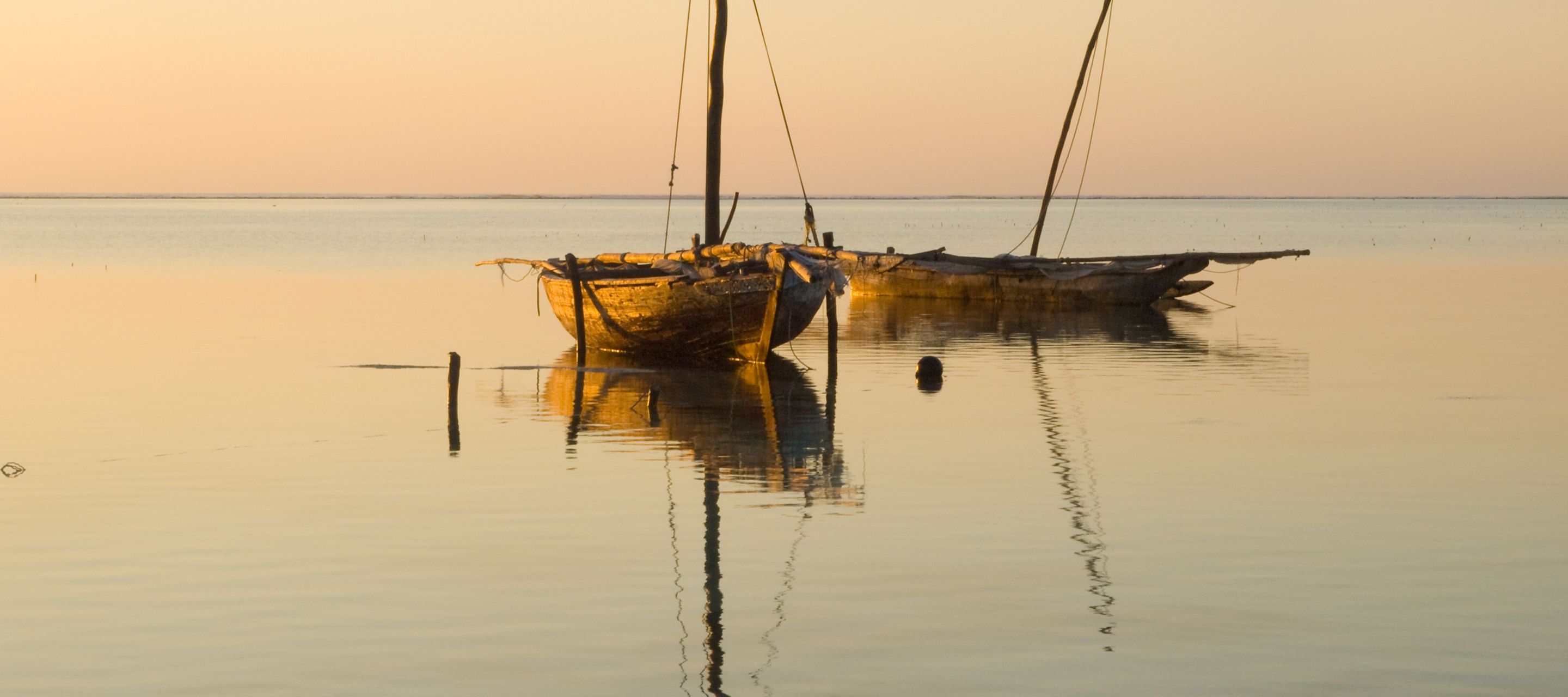 Traditionelle Boote im Sonnenaufgang an der Ostküste Sansibars