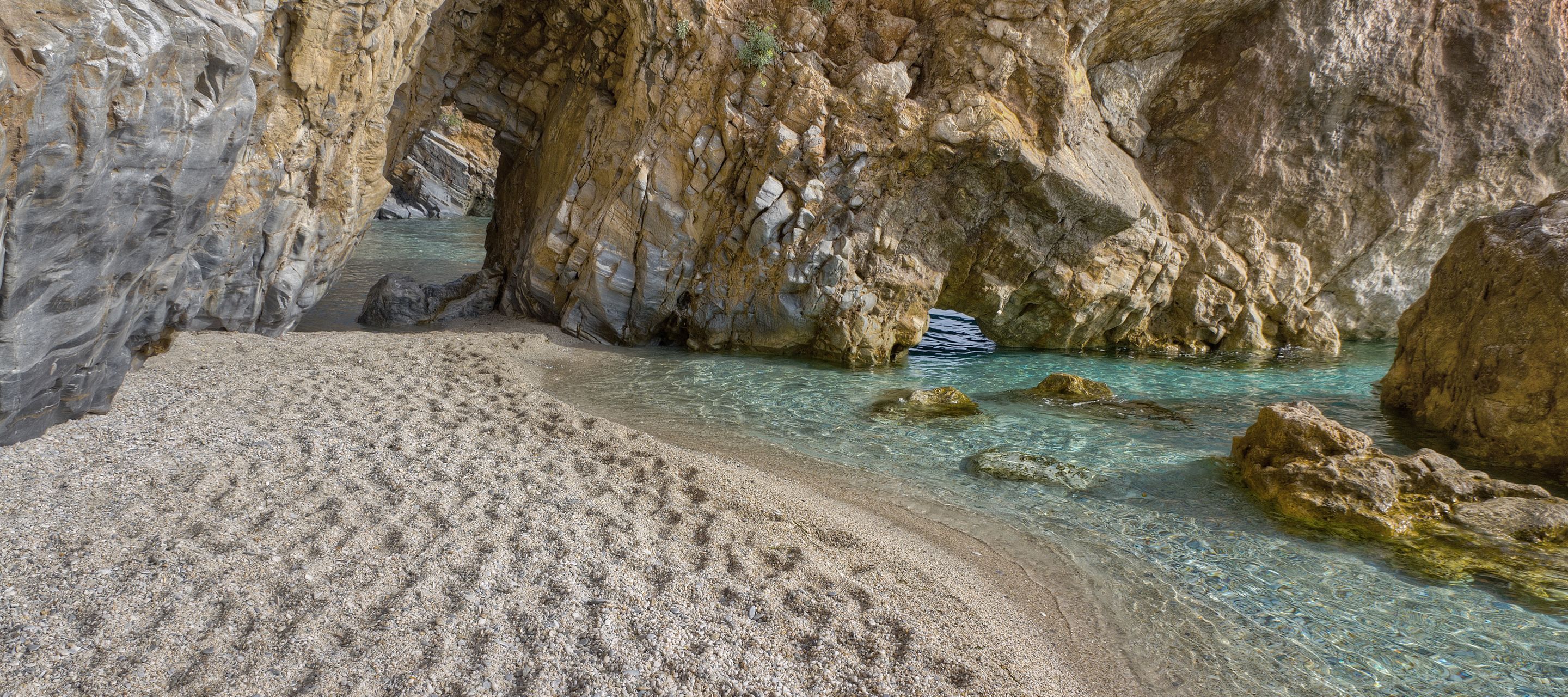 Weisser Kies, schroffe Felsformationen, ein Felsbogen und eine Meeresbrise mit Pinienwaldduft