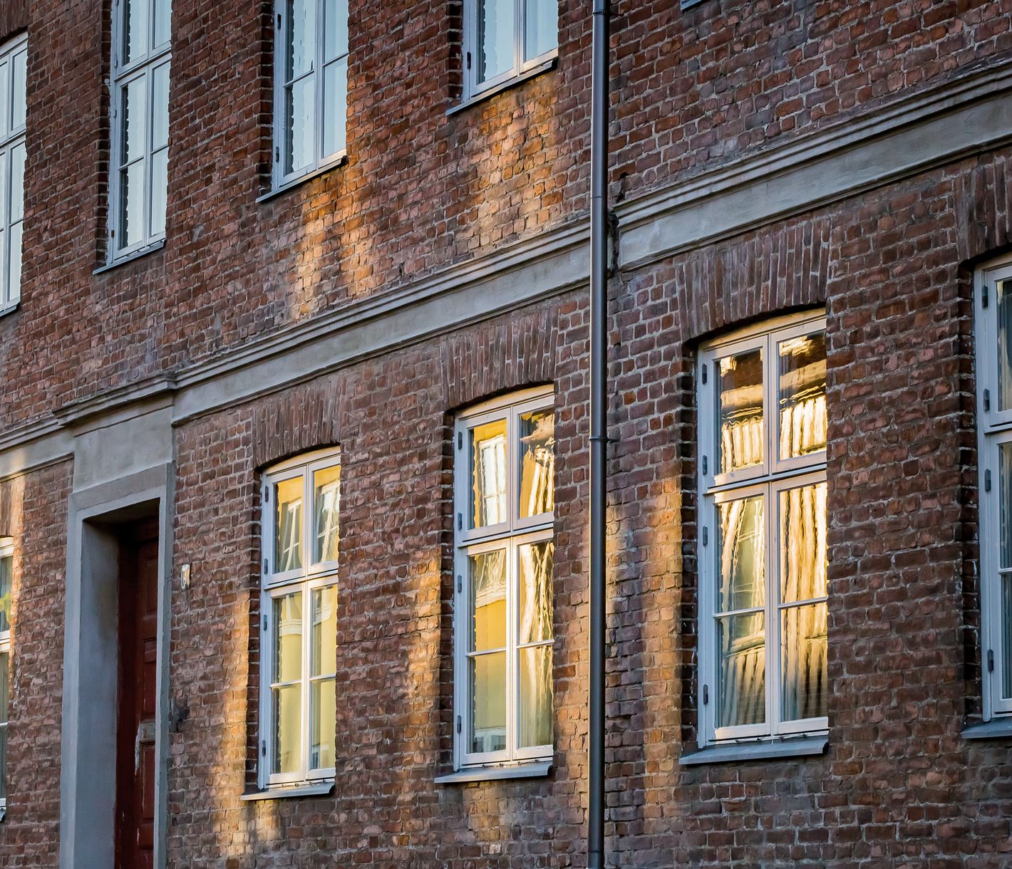 Rayons du soleil de minuit se mirant sur les fenêtres d’une maison à Trondheim