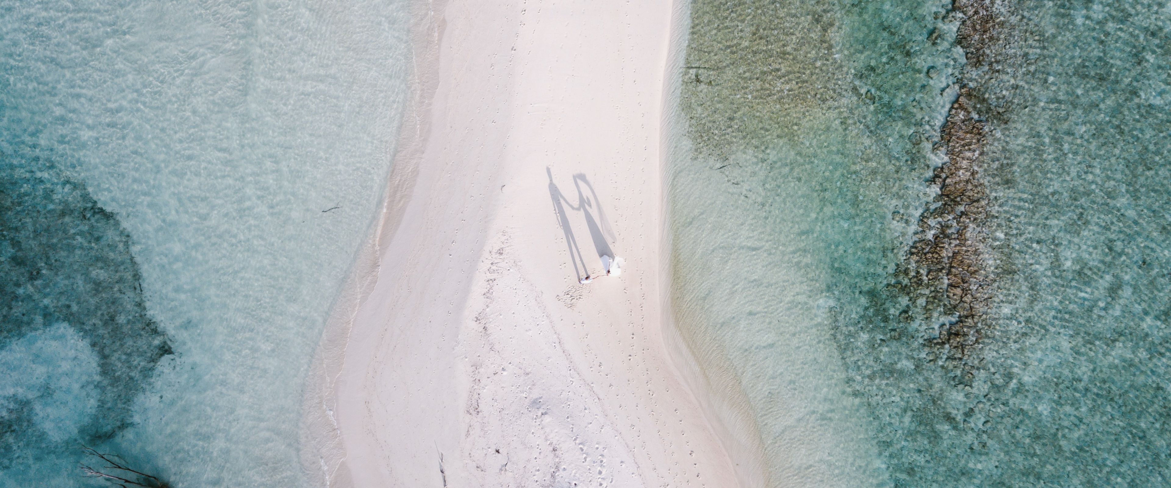 Hand in Hand über Sand, wo die Welt nur Himmel und Meer kennt.