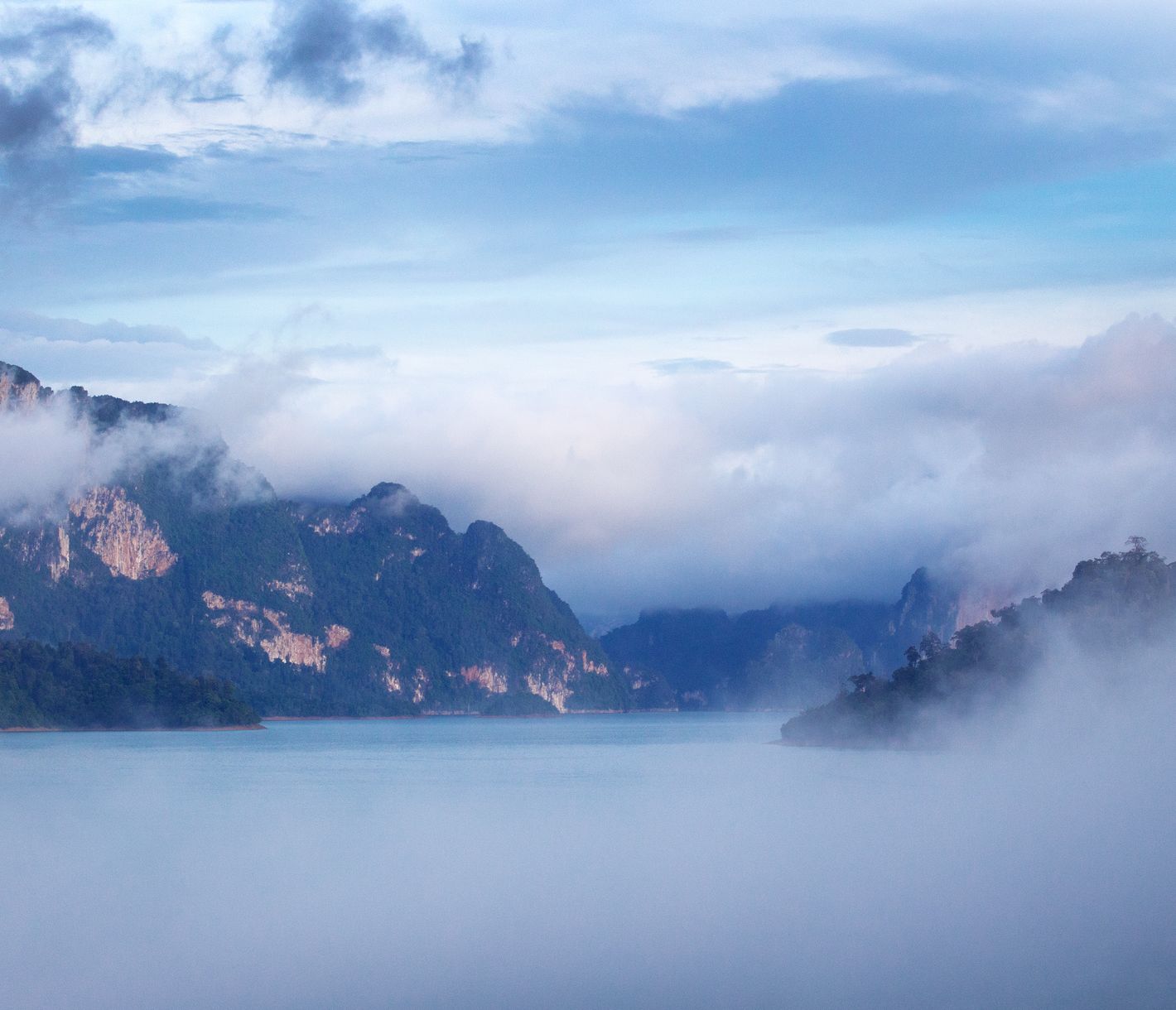Nebel durchzieht die dicht bewaldeten Karstfelsen am Cheow-Larn-See.