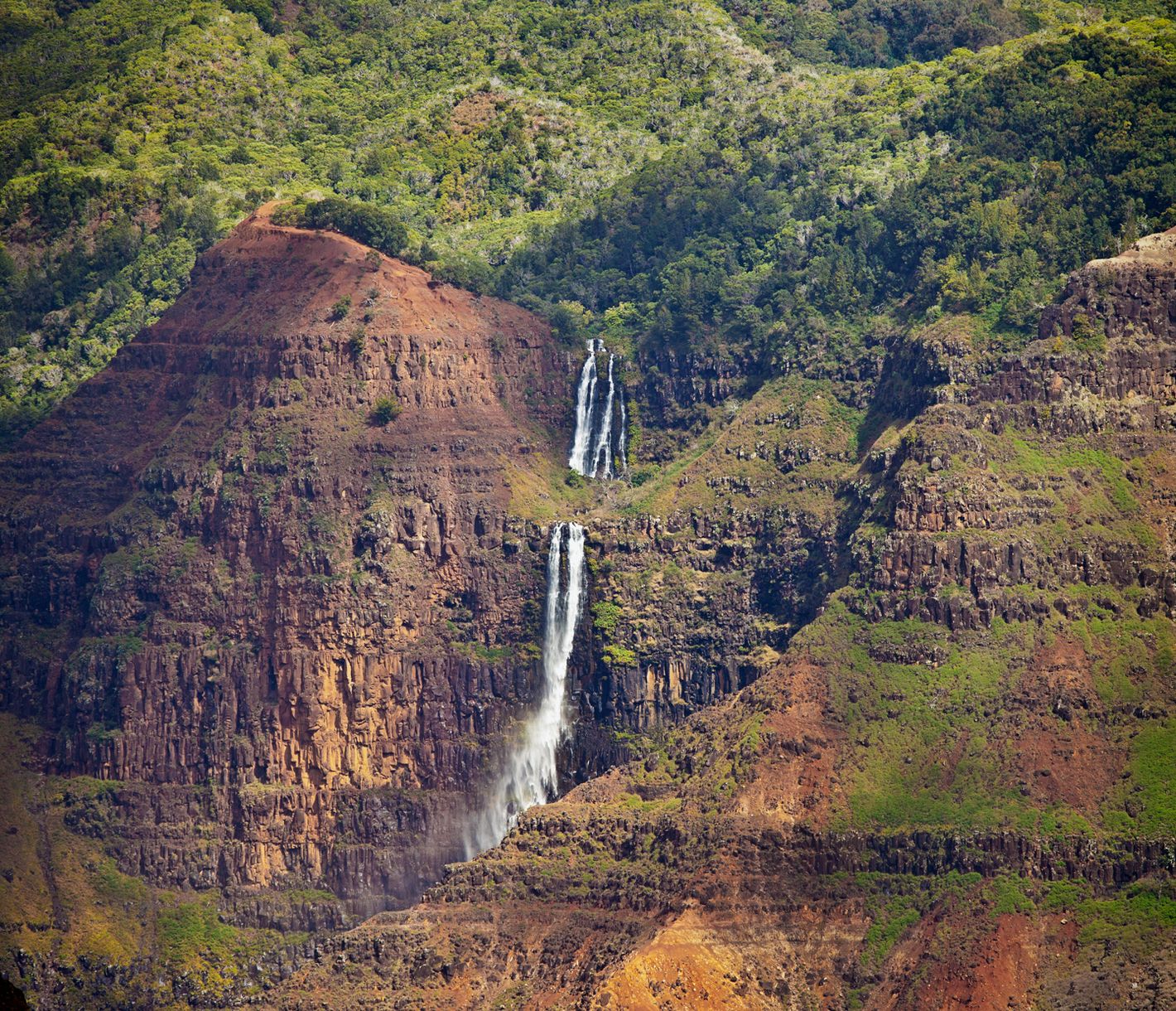 Der Waimea Canyon auf Kauai beeindruckt mit leuchtend roten Felsen, tiefen Schluchten und weiten Ausblicken über die zerklüftete Landschaft.