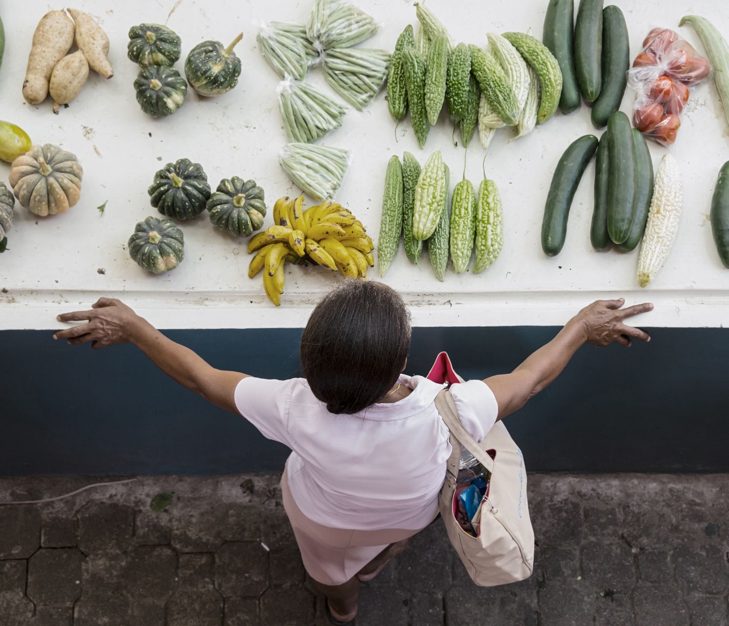 Eine Frau betrachtet Gemüse an einem Stand auf dem zentralen Markt in Victoria.