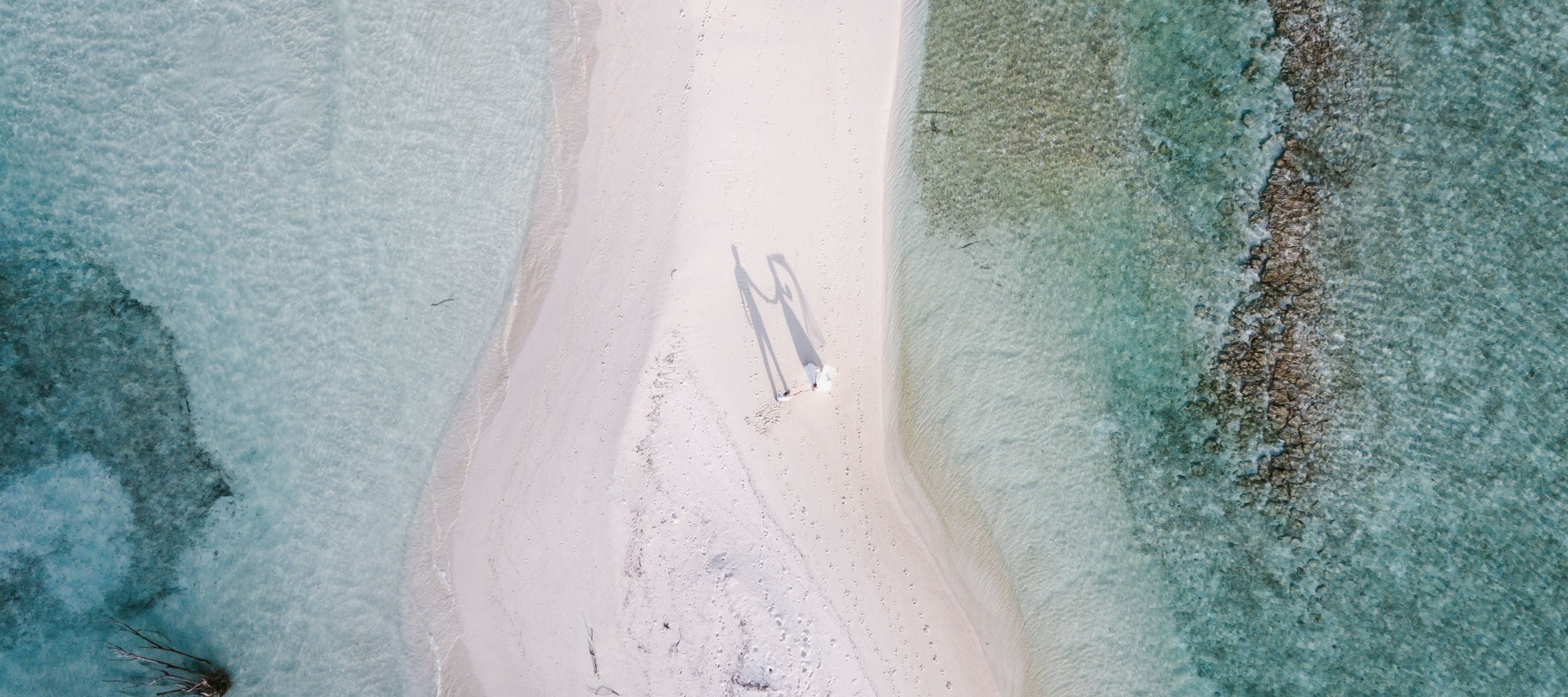 Hand in Hand über Sand, wo die Welt nur Himmel und Meer kennt.