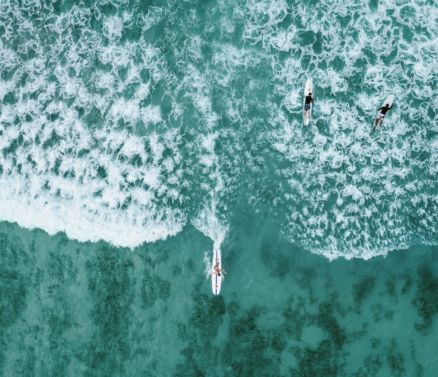 Frühmorgens, bereits vor Sonnenaufgang, sind die ersten Surfer auf dem Wasser und warten auf die perfekte Welle.
